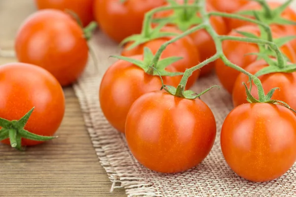 Haufen Kirschtomaten, auf Holzoberfläche und Tuch — Stockfoto