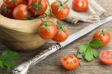 Yığın kiraz domates kase, bıçak ve bazı ahşap yüzeyde ikiye böldüm.