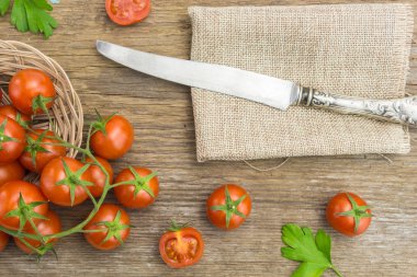 Yığın kiraz domates hasır kase, bıçak ve bazı ahşap yüzeyde ikiye böldüm.