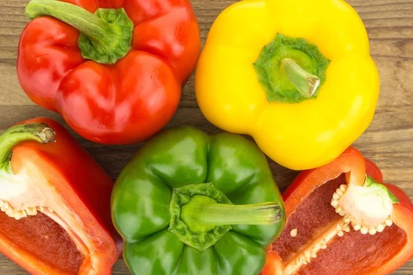 Fresh red,  yellow and green bell peppers, on wooden surface.
