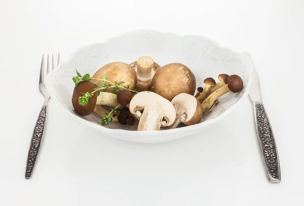 Cogumelos de botão e cogumelo faia marrom em tigela com garfo e faca, sobre fundo branco . — Fotografia de Stock