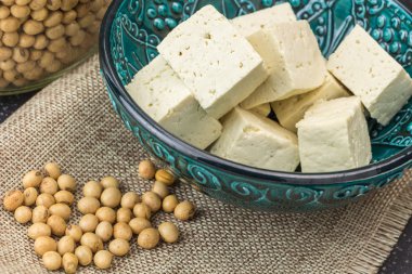 Küpleri ve soya fasulyesi, ahşap arka plan üzerinde oyulmuş tofu.