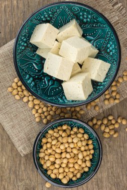 Küpleri ve soya fasulyesi kase, ahşap arka plan üzerinde oyulmuş tofu.
