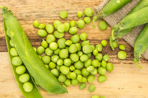 Kumaş ve ahşap yüzey üzerinde taze yeşil bezelye