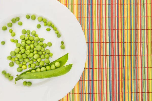 Verse doperwtjes op plaat, op kleurrijke bamboe placemat — Stockfoto