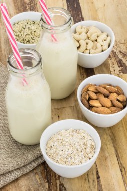 Ev yapımı bitki şişe süt ve kase malzemelerle, ahşap arka plan üzerine dayalı
