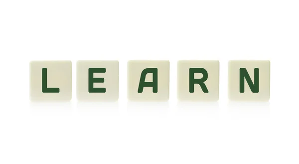 Word "Learn" on board game square plastic tile pieces, isolated on a white background. — Stock Photo, Image