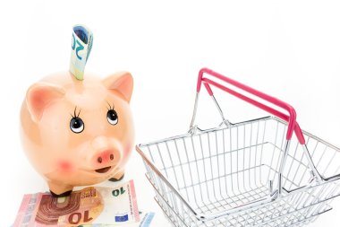 Para ve beyaz arka plan üzerinde boş alışveriş sepeti ile Piggy banka