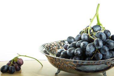 Üzüm, beyaz arka plan ile ahşap yüzey üzerinde küme ile antika meyve kase.