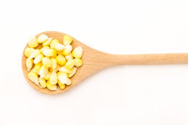 Beyaz zemin üzerine tahta kaşık Mısır taneleri.