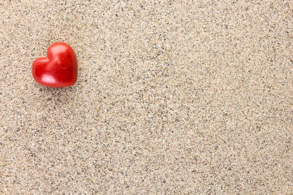 Red heart shaped stone on sand surface with copy-space — Stock Photo, Image