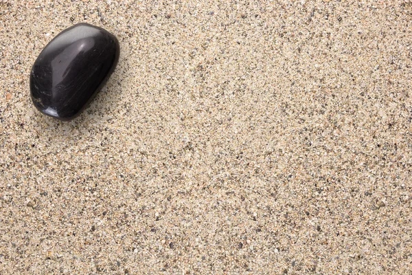 복사-스페이스 모래 표면에 검은 현무암 돌 — 스톡 사진