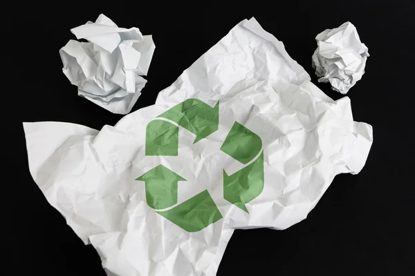 Crumpled paper sheet with Recycling Symbol isolated on black — Stock Photo, Image
