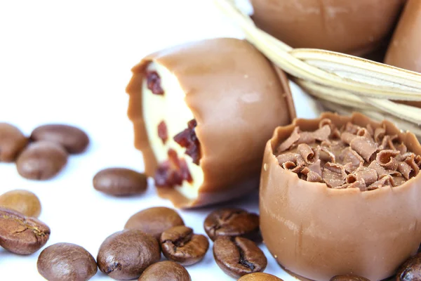 Produtos de confeitaria de chocolate variados com grãos de café isolados em branco — Fotografia de Stock