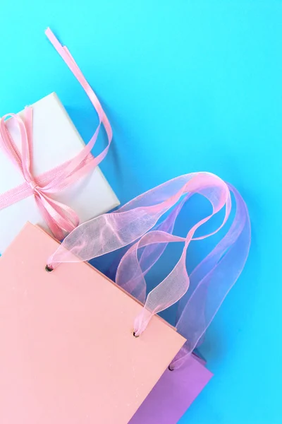 Renkli alışveriş torbaları ve açık mavi renkli üzerinde hediye kutusu — Stok fotoğraf