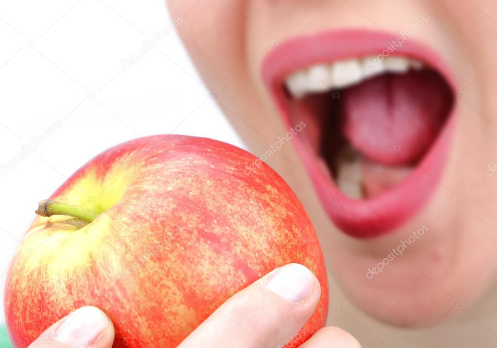 Closeup of womans mouth biting an apple on white background 
