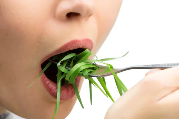 Woman with fork eating wheatgrass, isolated on white. — Stock Photo, Image