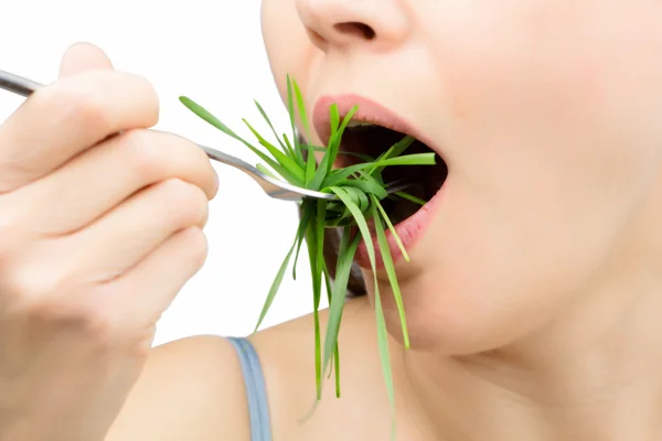 Woman with fork eating wheatgrass as spaghetti, isolated on white. — Stock Photo, Image