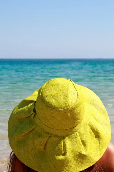 Jovem senhora com chapéu olhando para o mar e céu azul — Fotografia de Stock