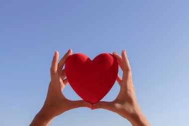 Kırmızı kalp ile holding eller açık mavi gökyüzü ve boşluk