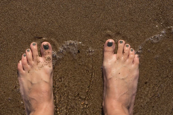 Los pies húmedos femeninos por el agua sobre la arena — Foto de Stock