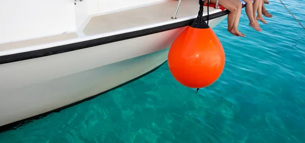 Vom unteren Teil eines Bootes mit herabhängenden Beinen der Passagiere und türkisfarbenem Meer — Stockfoto