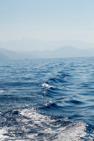 Paisaje marino con montañas lejanas, cielo y agua de mar ondulada — Foto de Stock