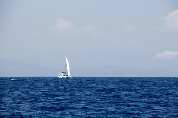 Barco de vela, montañas distantes y nubes esponjosas — Foto de Stock