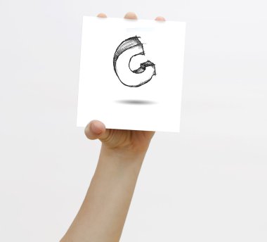 Hand holding a piece of paper with sketchy capital letter G, isolated on white.