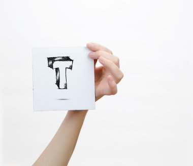 Hand holding a piece of paper with sketchy capital letter  T, isolated on white.