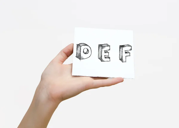 Hand holding a piece of paper with sketchy capital letters  D E F, isolated on white. — Stockfoto