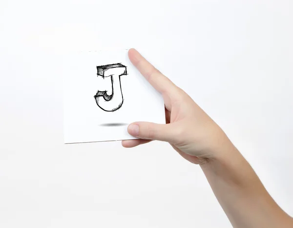 Hand holding a piece of paper with sketchy capital letter J, isolated on white. — Stockfoto