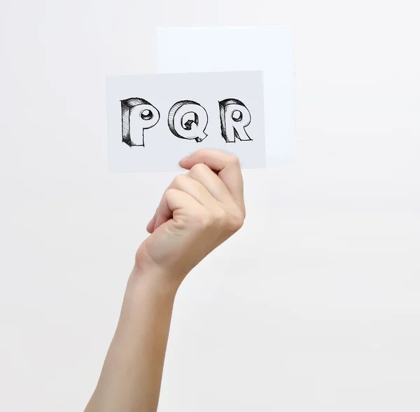 Hand holding a piece of paper with sketchy capital letters  P Q R, isolated on white. — Stok fotoğraf
