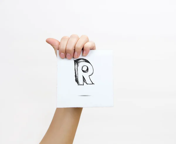 Hand holding a piece of paper with sketchy capital letter  R, isolated on white. — Stok fotoğraf