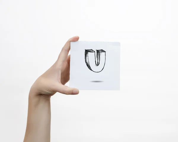 Hand holding a piece of paper with sketchy capital letter  U, isolated on white. — Stok fotoğraf