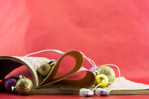 Libro de notación musical con páginas que conforman el corazón con auriculares y adornos navideños — Foto de Stock