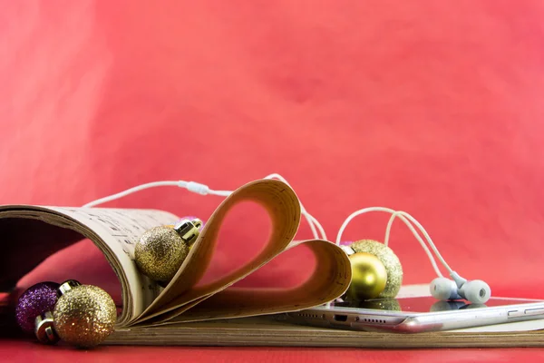 Music notation book with pages shaping heart with earphones and Christmas ornaments — Stock Photo, Image