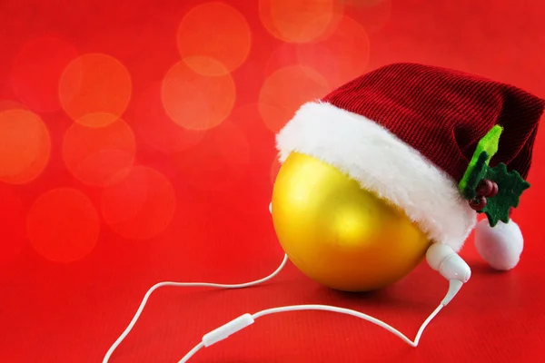 Christmas ball with Santa's hat and earphones, on red with bokeh lights — Stock Photo, Image