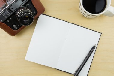 Eski fotoğraf makinesi, defter, kalem ve bir fincan kahve ahşap yüzey üzerinde