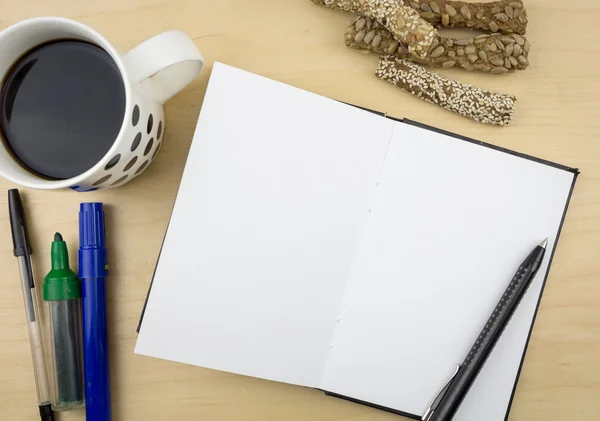 Offenes Notizbuch mit Stift, einer Tasse Kaffee und einigen Schlagstöcken mit Samen, auf Holzoberfläche. — Stockfoto