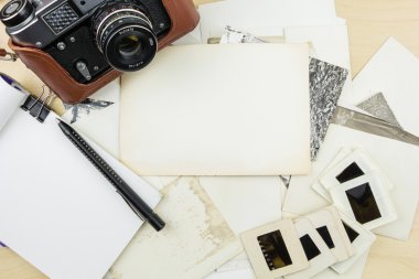 Eski fotoğraf makinesi, not defteri ve kalem fotoğraf ve şeffaflık slayt yığını üzerinde