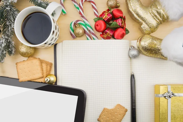 Tablet e caderno aberto, com xícara de café e ornamentos festivos de inverno . — Fotografia de Stock