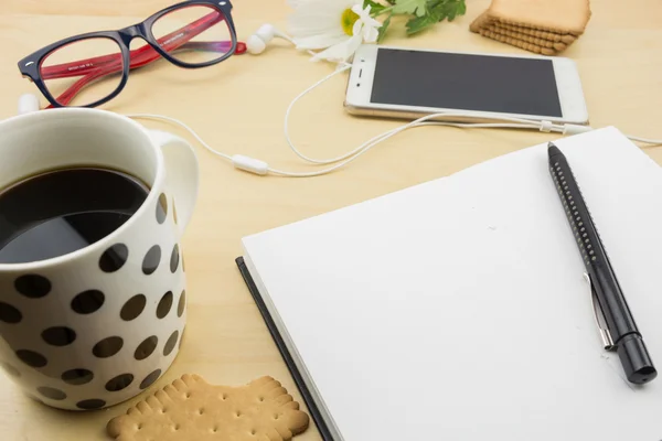 Lege notebook met pen, smartphone en kopje koffie en koekjes, op houten bureaublad geopend. — Stockfoto