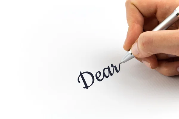 Hand skriver "Kära" på vitt papper. — Stockfoto