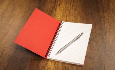 ahşap bir masa üzerine kalem ile not defteri