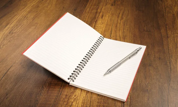 ahşap bir masa üzerine kalem ile not defteri