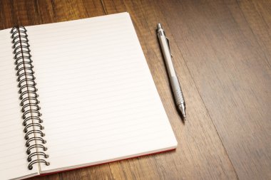 ahşap bir masa üzerine kalem ile not defteri