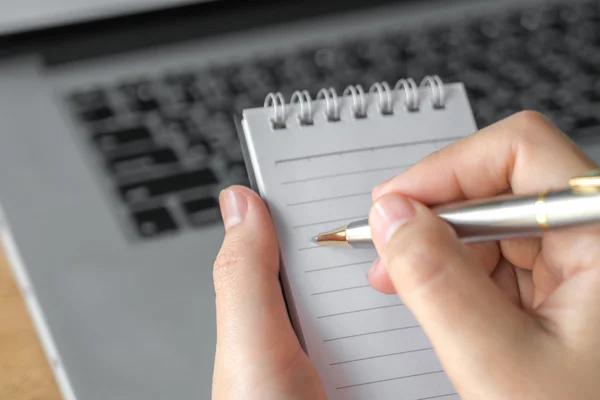 Frauenhand mit Bleistift über Laptop notiert — Stockfoto