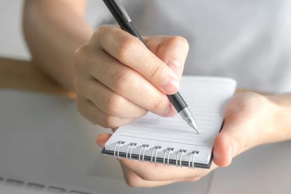 Frauenhand mit Bleistift über Laptop notiert — Stockfoto