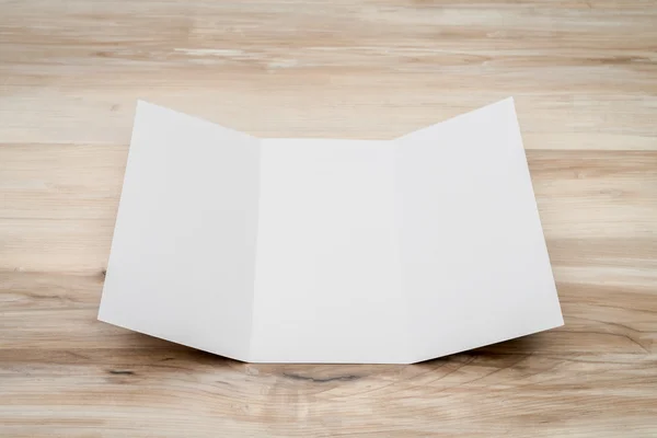 Tríptico papel de plantilla blanco sobre textura de madera —  Fotos de Stock